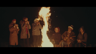 Group of people assembled around a fire for a ceremony.