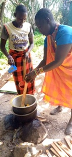 Two Maasai women cooking a traditional dish.