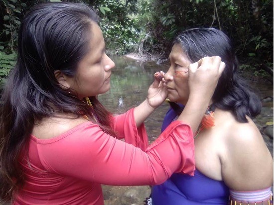 Young woman helping an older woman put on traditional makeup