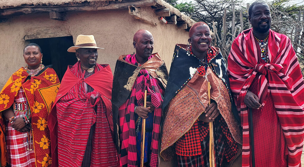 Group of Maasai people colorfully dressed smiling and welcoming visitors. 