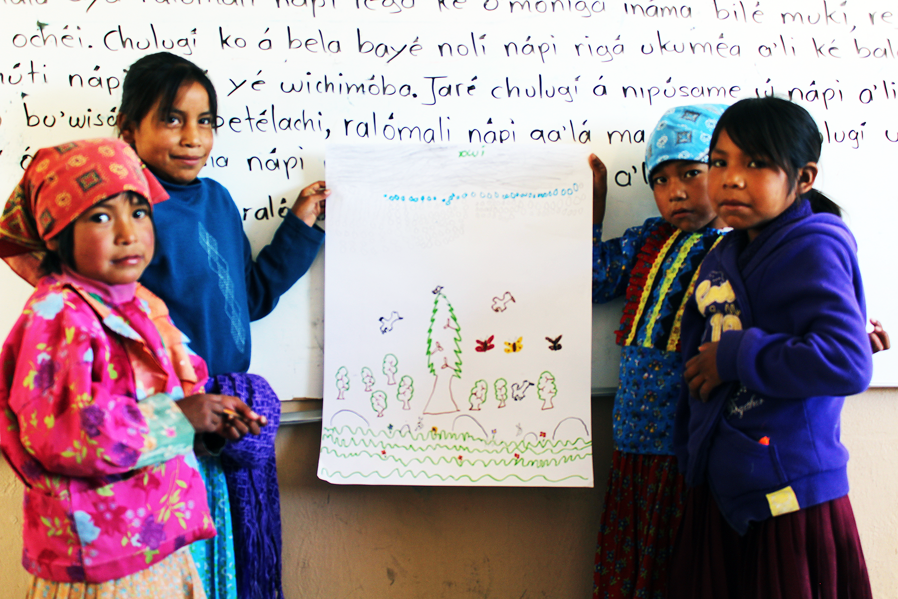 Photo of a group of young children in a classroom proudly displaying the project they've been working on.