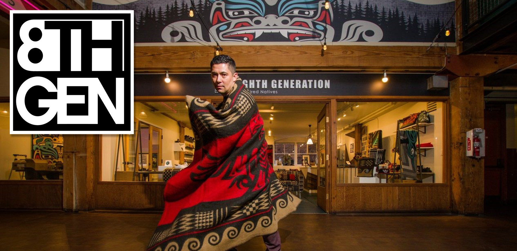 Photo of 8Th Generation  founder Louie Gong wearing one of his wool blankets like a superhero cape while standing in front of his Seattle store. 